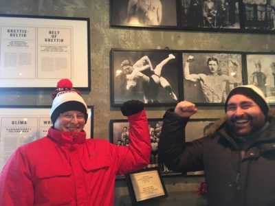 Weak armed men flexing in front of a wrestling exhibit